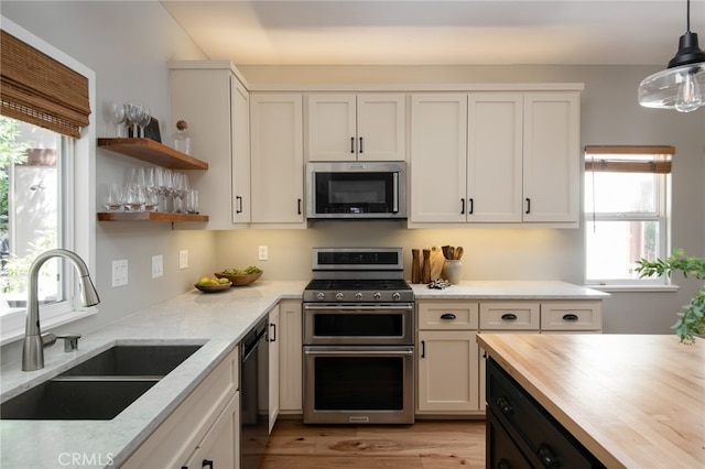 kitchen with white cabinetry, a sink, wooden counters, and appliances with stainless steel finishes