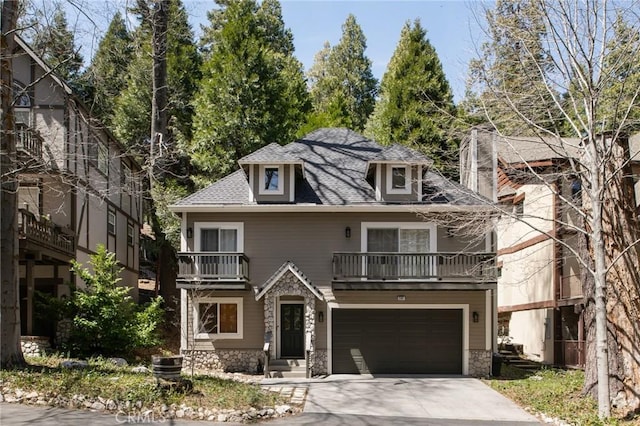 view of front of house featuring stone siding, concrete driveway, an attached garage, a shingled roof, and a balcony