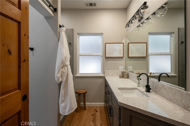 bathroom featuring baseboards, visible vents, wood finished floors, a shower, and vanity