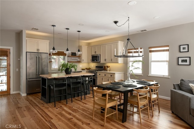 dining room with light wood-type flooring, baseboards, a notable chandelier, visible vents, and recessed lighting