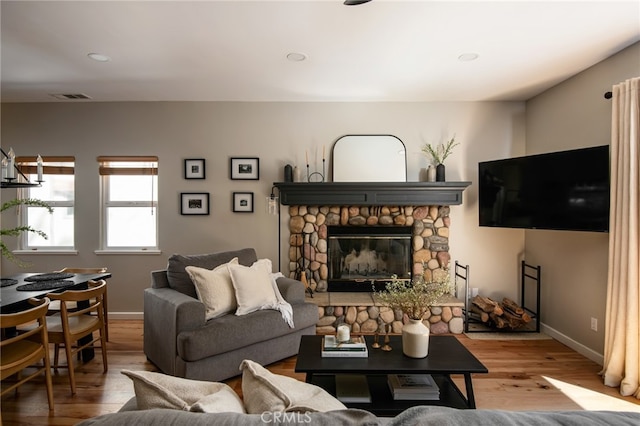 living room featuring wood finished floors, a fireplace, baseboards, visible vents, and recessed lighting