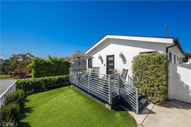 view of property exterior featuring a lawn, stucco siding, and fence