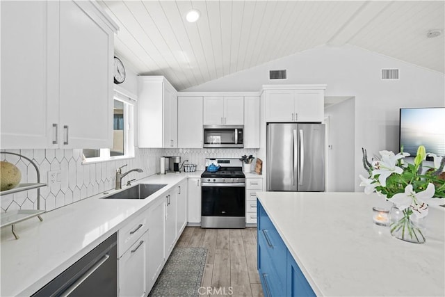 kitchen featuring lofted ceiling with beams, appliances with stainless steel finishes, a sink, and visible vents