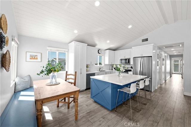 kitchen featuring lofted ceiling, light countertops, a sink, a kitchen island, and appliances with stainless steel finishes