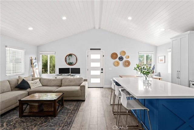 living room with plenty of natural light, hardwood / wood-style floors, vaulted ceiling with beams, and recessed lighting