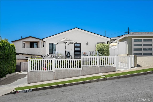 view of front facade featuring stucco siding, an attached garage, and a fenced front yard