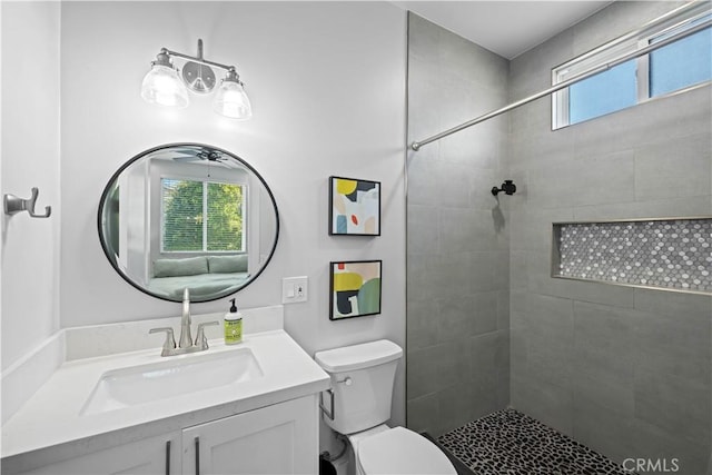 bathroom with toilet, vanity, and a tile shower