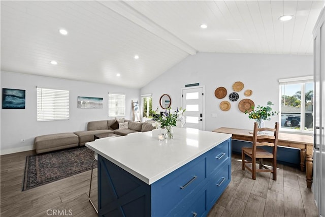kitchen featuring blue cabinets, lofted ceiling with beams, a kitchen breakfast bar, recessed lighting, and wood finished floors