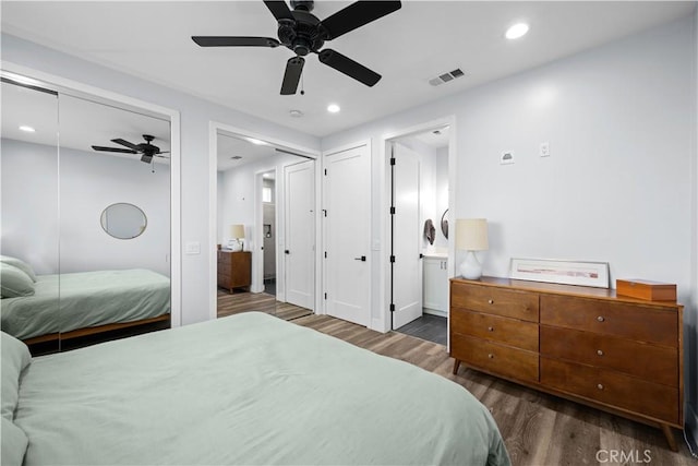 bedroom featuring visible vents, recessed lighting, wood finished floors, ceiling fan, and multiple closets