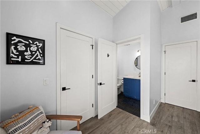 hall with lofted ceiling, wood finished floors, visible vents, and a sink