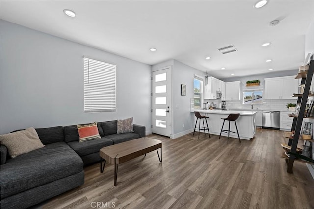 living room featuring baseboards, visible vents, dark wood-style floors, and recessed lighting