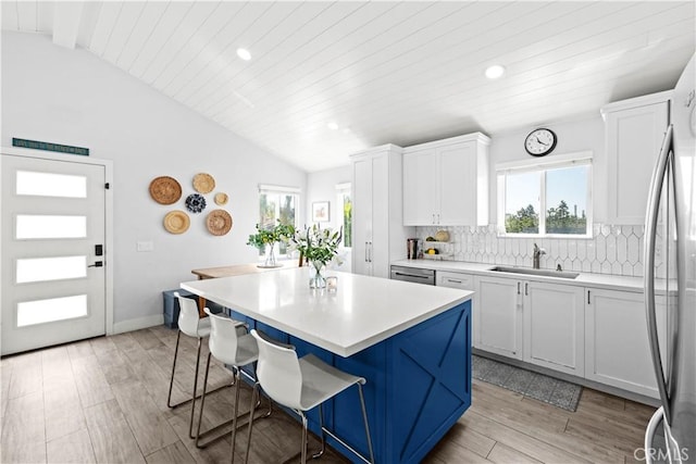 kitchen with vaulted ceiling with beams, a sink, tasteful backsplash, and a kitchen breakfast bar
