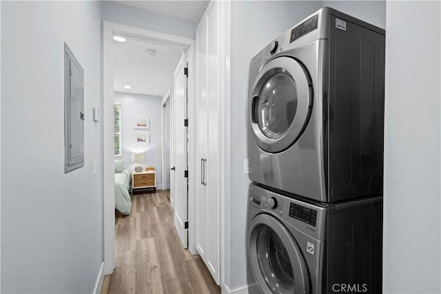 laundry room with recessed lighting, laundry area, wood finished floors, stacked washing maching and dryer, and baseboards