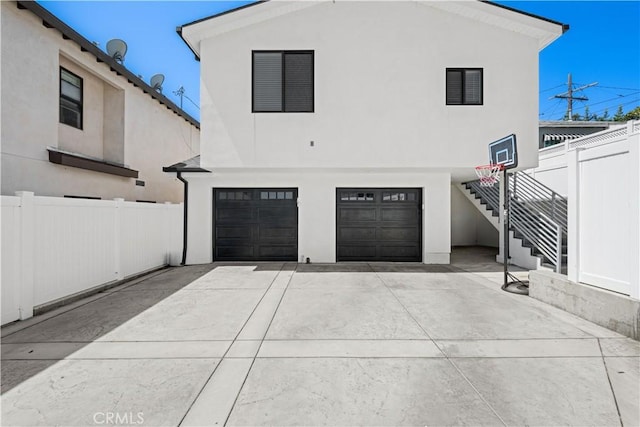 exterior space with driveway, fence, an attached garage, stairway, and stucco siding