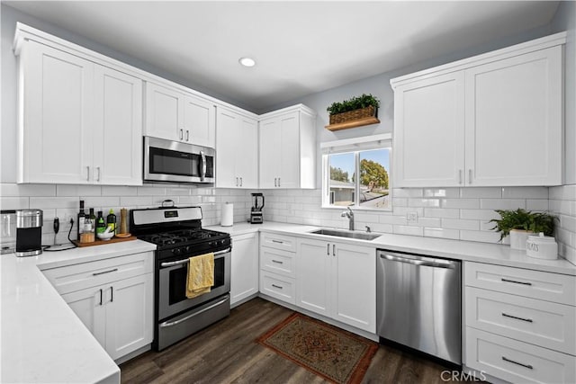 kitchen featuring recessed lighting, light countertops, a sink, appliances with stainless steel finishes, and white cabinetry