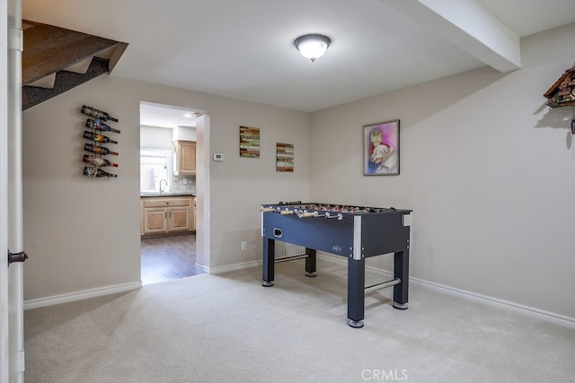 game room with a sink, light colored carpet, and baseboards
