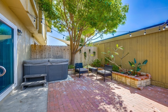 view of patio featuring fence and a hot tub