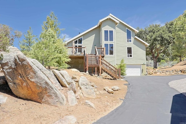 view of front of property featuring a garage, driveway, a wooden deck, and stairs