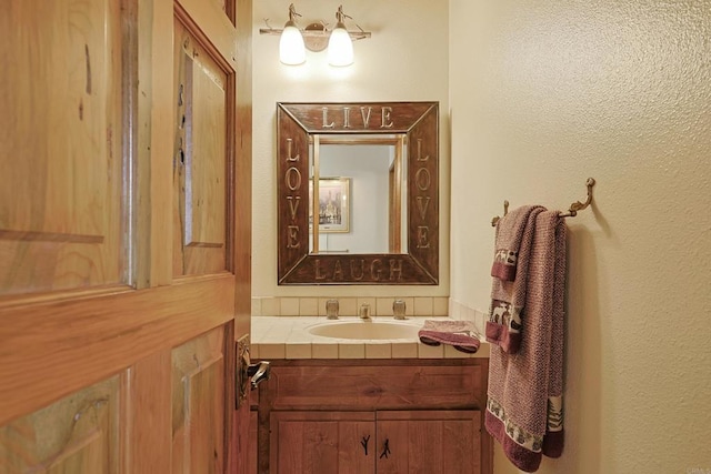 bathroom with a textured wall and vanity