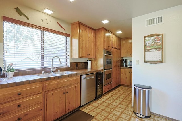 kitchen featuring a sink, tile countertops, light floors, stainless steel appliances, and visible vents