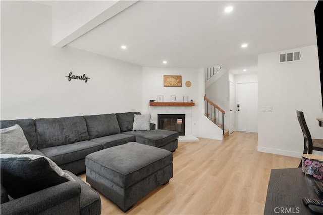 living room with light wood finished floors, baseboards, visible vents, recessed lighting, and stairs