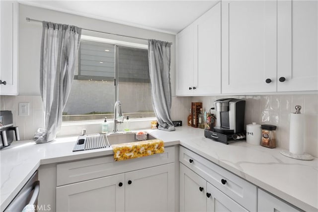 kitchen featuring tasteful backsplash, stainless steel dishwasher, white cabinetry, and a sink