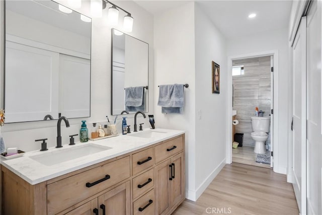 full bath with wood finished floors, baseboards, a sink, and toilet