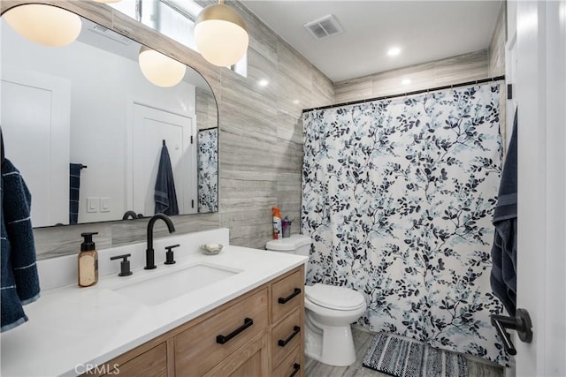 full bath featuring toilet, a shower with curtain, vanity, and visible vents