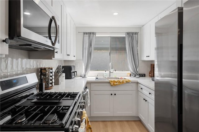 kitchen with light countertops, appliances with stainless steel finishes, white cabinetry, and a sink