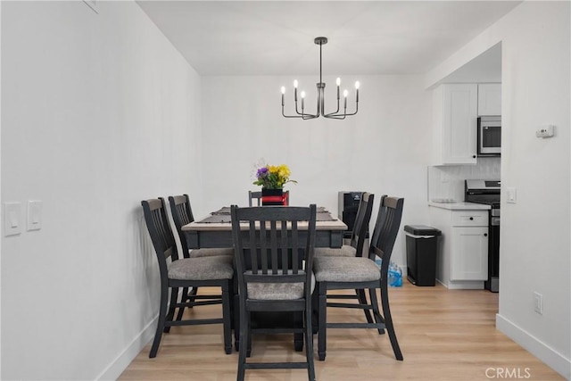 dining room with light wood-style flooring, baseboards, and an inviting chandelier