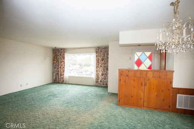 empty room featuring a chandelier, carpet floors, and visible vents