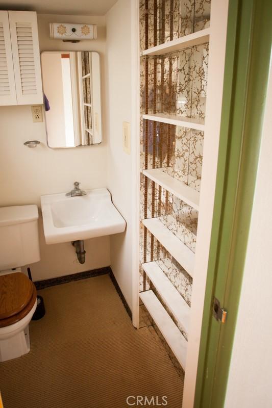 half bath featuring baseboards, a sink, and toilet