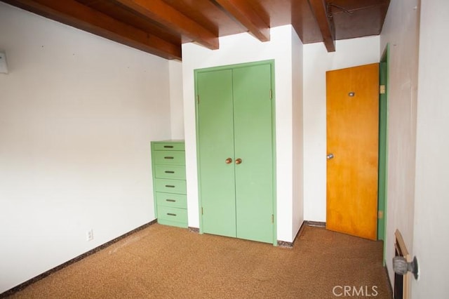 unfurnished bedroom featuring carpet floors, beam ceiling, and a closet