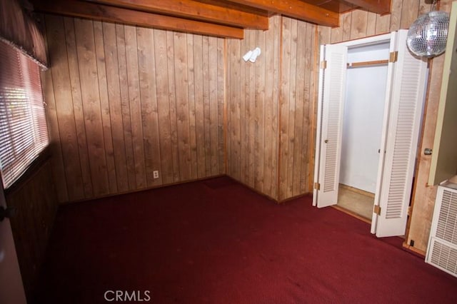 unfurnished bedroom with wood walls, visible vents, and carpet