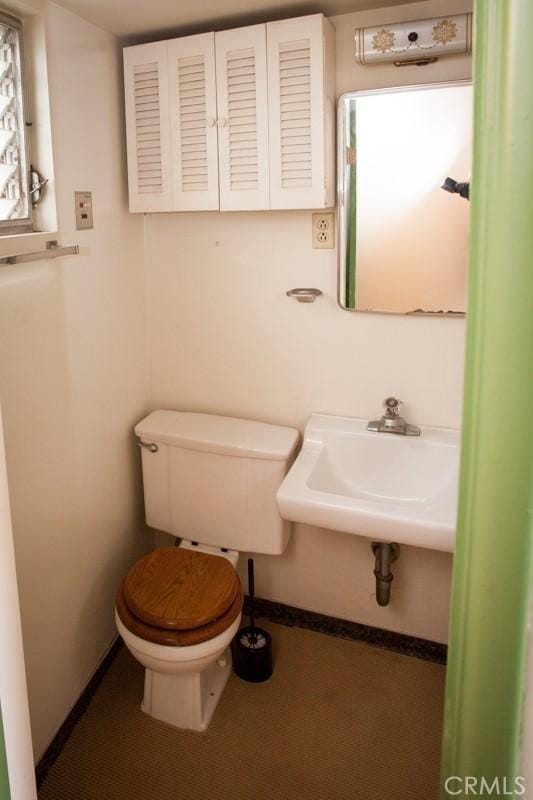 bathroom with toilet, baseboards, and a sink