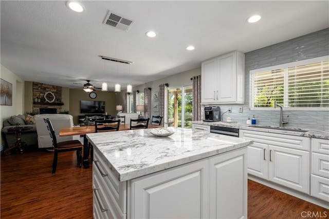 33077 Monte Dr, Temecula, CA 92592 - kitchen featuring a kitchen island, a ceiling fan, a stone fireplace, visible vents, and a sink