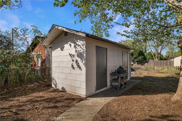 view of outbuilding featuring fence and an outbuilding