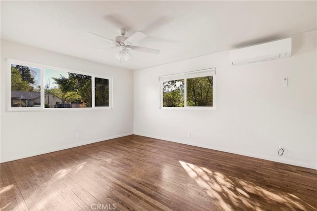 unfurnished room featuring a wealth of natural light, hardwood / wood-style flooring, a wall mounted AC, and a ceiling fan