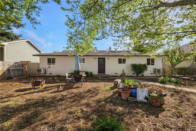 back of property featuring a fire pit, fence, ac unit, and stucco siding