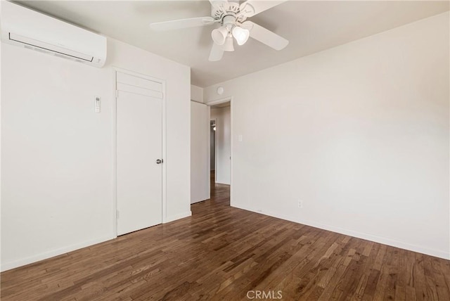 unfurnished bedroom featuring wood finished floors, a closet, an AC wall unit, and baseboards