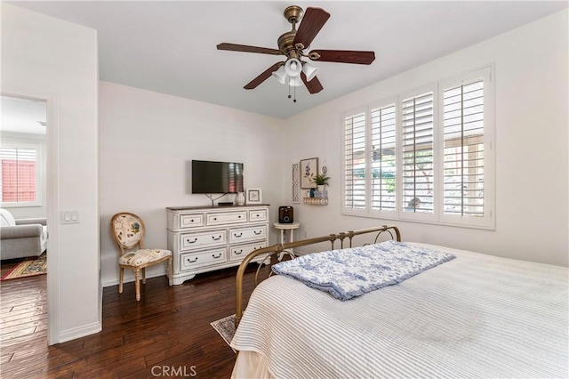 bedroom with dark wood-style flooring, a ceiling fan, and baseboards