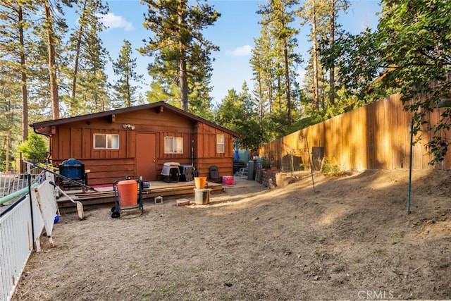 rear view of house with board and batten siding, fence, and a deck