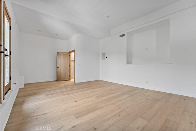 empty room with light wood finished floors, visible vents, and baseboards