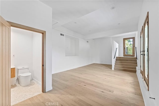 interior space with baseboards, visible vents, stairs, and light wood finished floors
