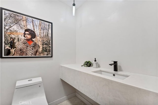 bathroom with toilet, baseboards, and a sink