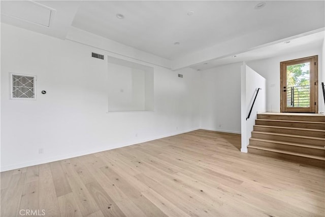 unfurnished living room featuring light wood finished floors, stairs, visible vents, and baseboards
