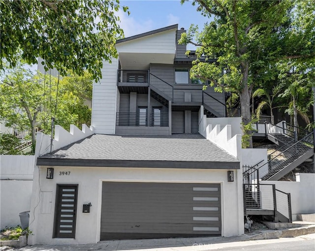 contemporary home with stairway, an attached garage, and stucco siding