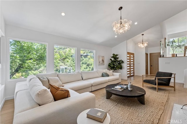 living room with baseboards, light wood-type flooring, a notable chandelier, and high vaulted ceiling