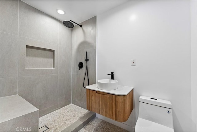 full bath with tiled shower, vanity, recessed lighting, and toilet