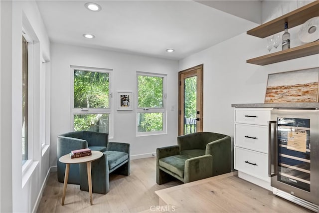 living area featuring baseboards, beverage cooler, light wood-style flooring, and recessed lighting
